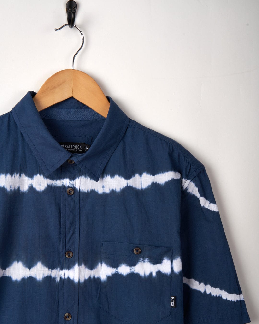 Ocean - Mens Tie Dye Shirt - Blue by Saltrock on a wooden hanger against a plain background.