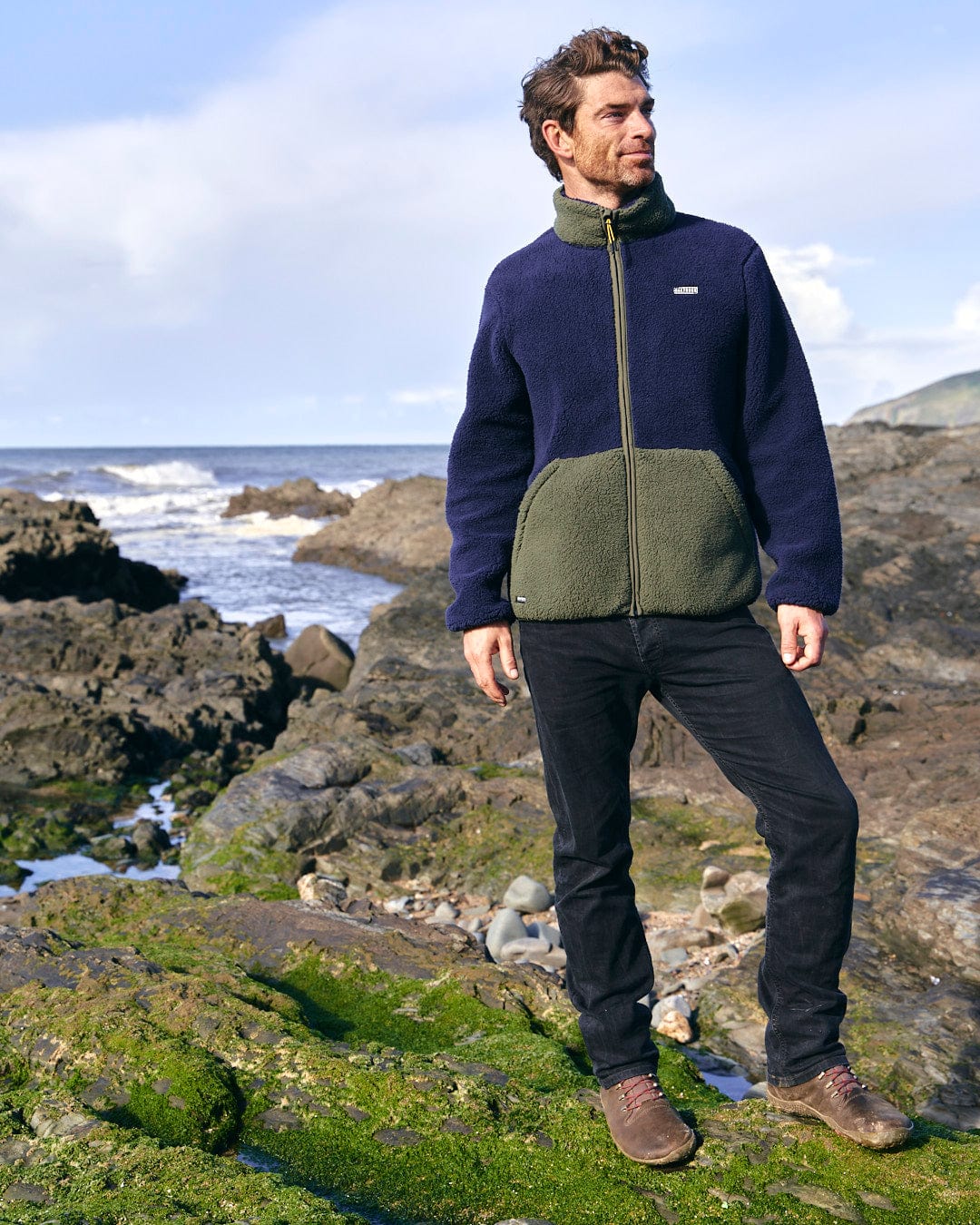 A man standing on a log in the woods wearing the Saltrock Odin - Mens Zip Thru Fleece - Dark Blue.