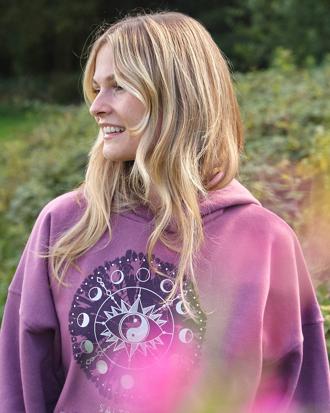 A woman in a purple Saltrock Ophelia - Womens Pop Hoodie smiling in a field.
