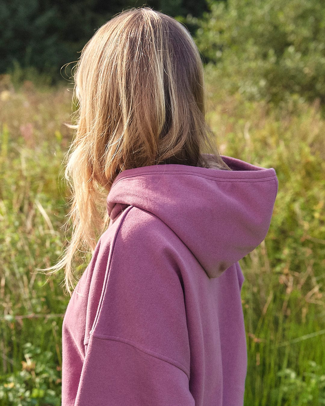 A woman wearing an Ophelia - Womens Pop Hoodie - Purple Saltrock hoodie stands in a field.