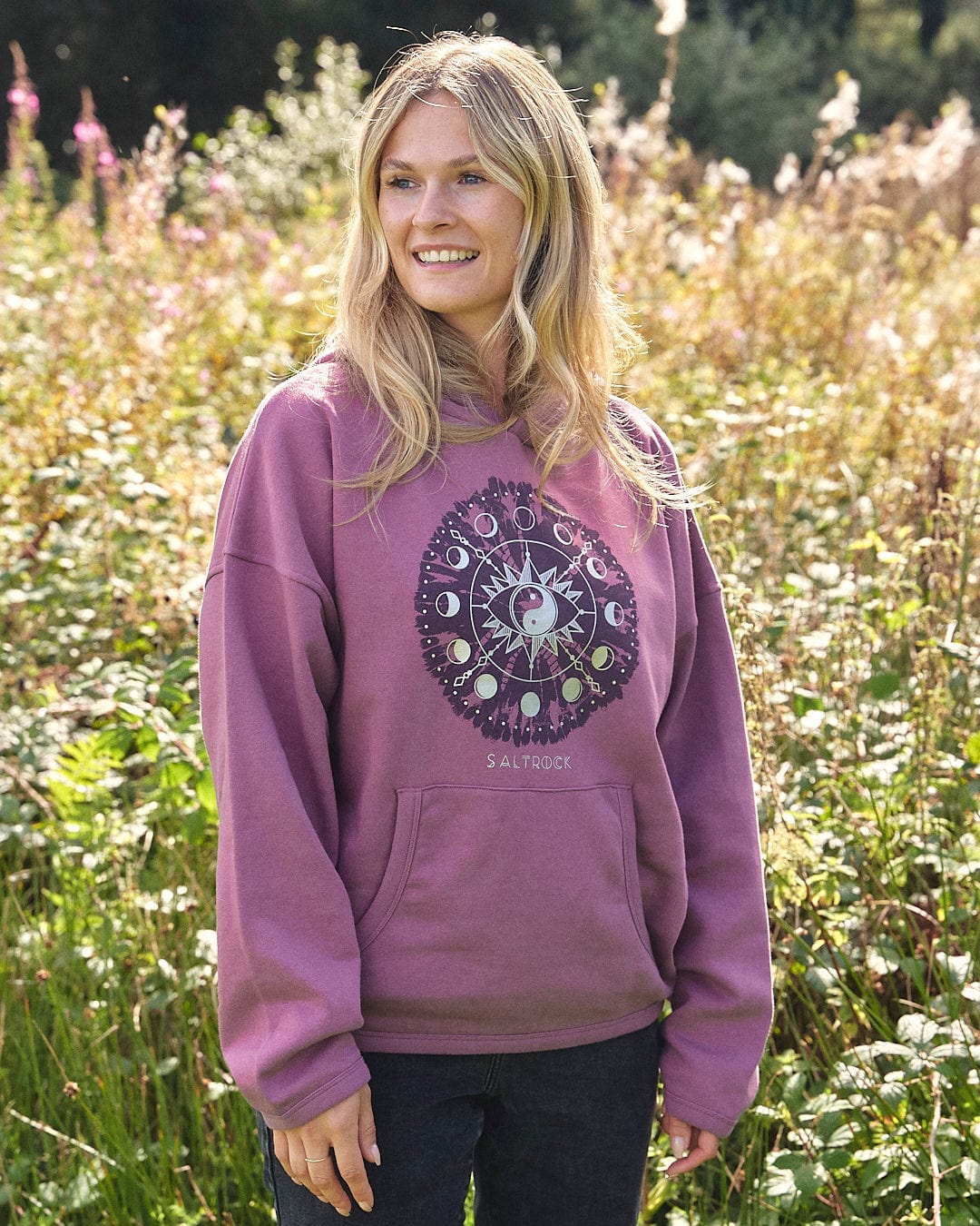 A woman wearing an Ophelia - Womens Pop Hoodie - Purple standing in a field.