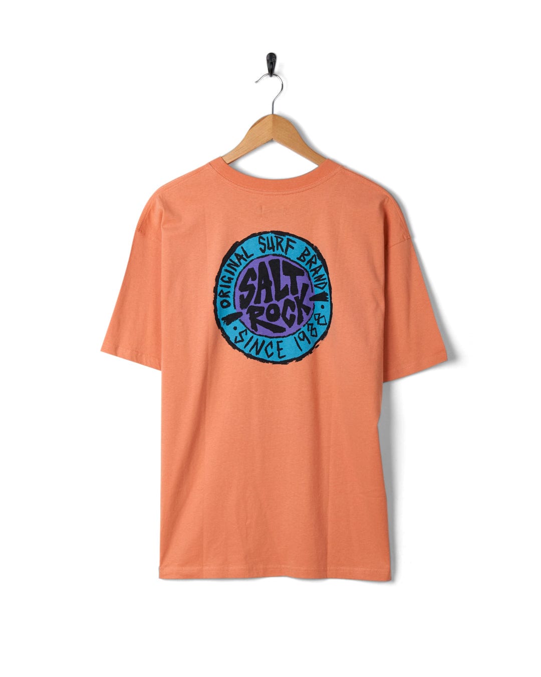 Peach Saltrock t-shirt with retro surf graphic print hanging on a white wall.