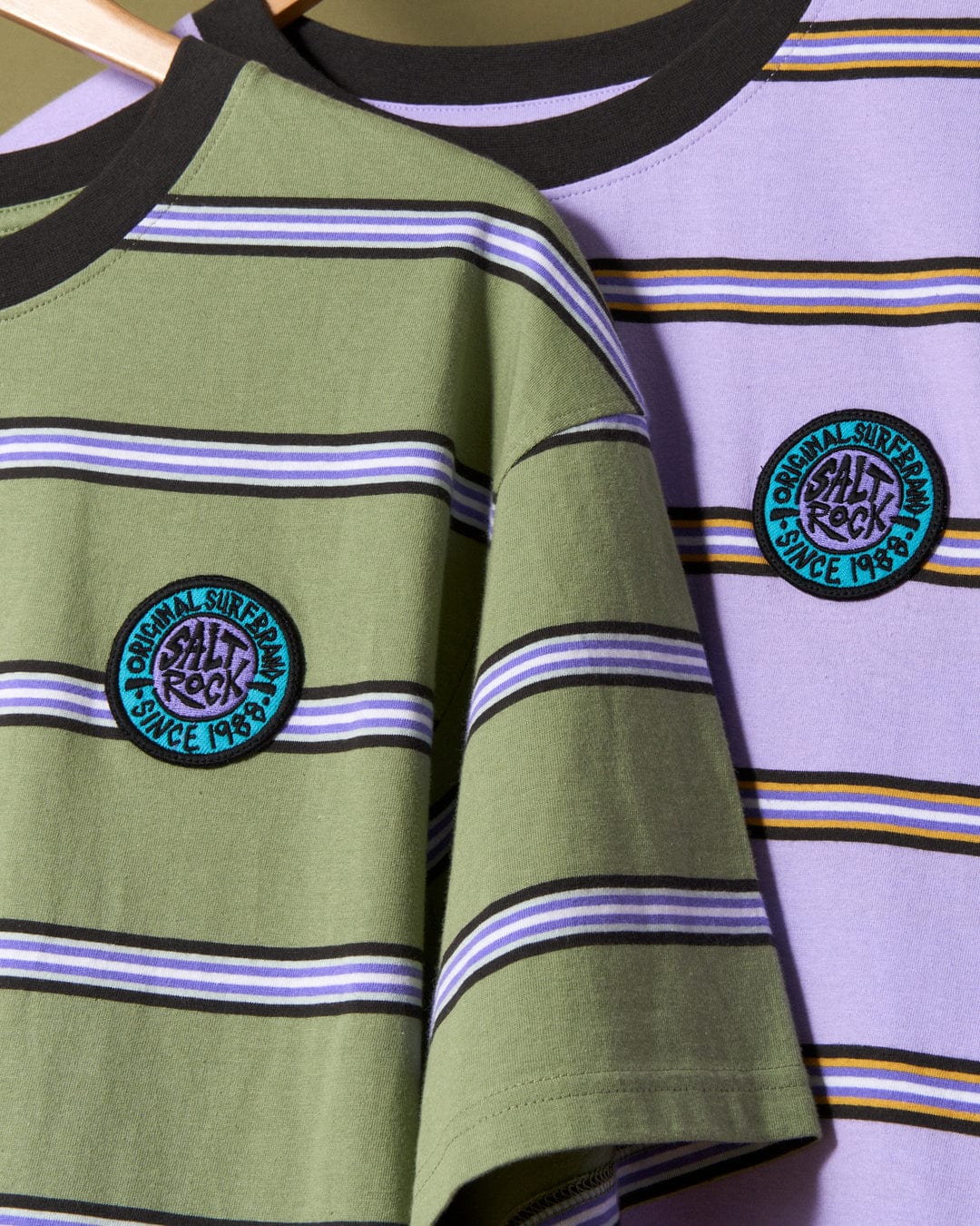 Striped casual SR Original - Mens Short Sleeve T-Shirts in Green with Saltrock branded embroidered patches displayed on wooden hangers.