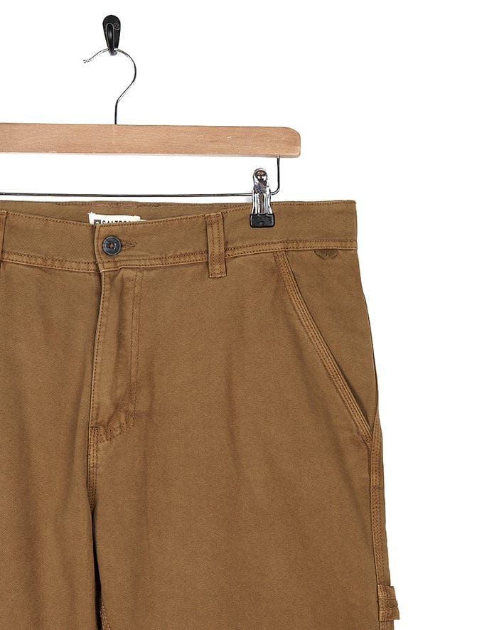 A pair of Oslo - Mens Carpenter Trouser - Brown shorts by Saltrock on a hanger.