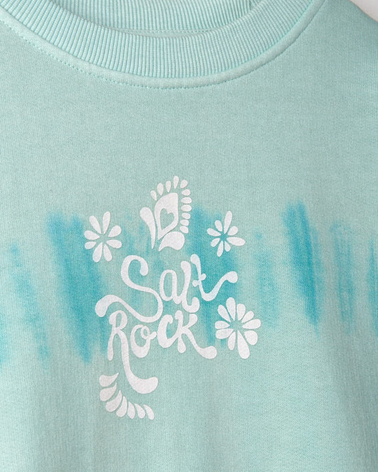 Close-up view of a light green fabric with a white "Peace Love Saltrock" illustration surrounded by flower motifs showcasing the Peace Love - Kids Sweat - Green from Saltrock.