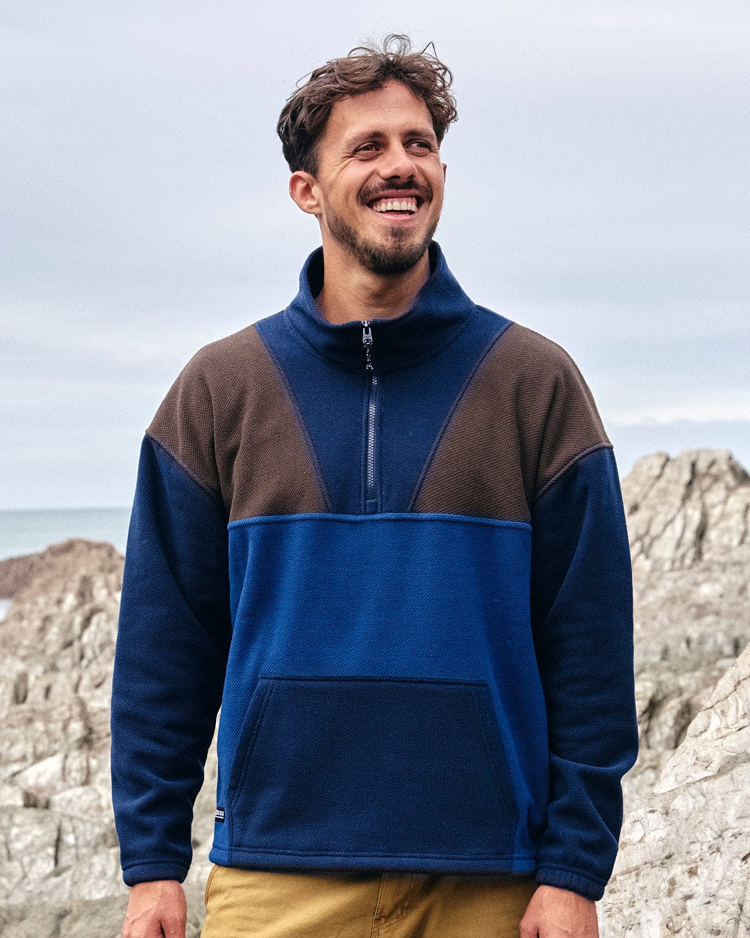 A man wearing a Saltrock Peninsula - Mens 1/4 Zip Pullover Fleece - Blue, showcasing his style in activewear.