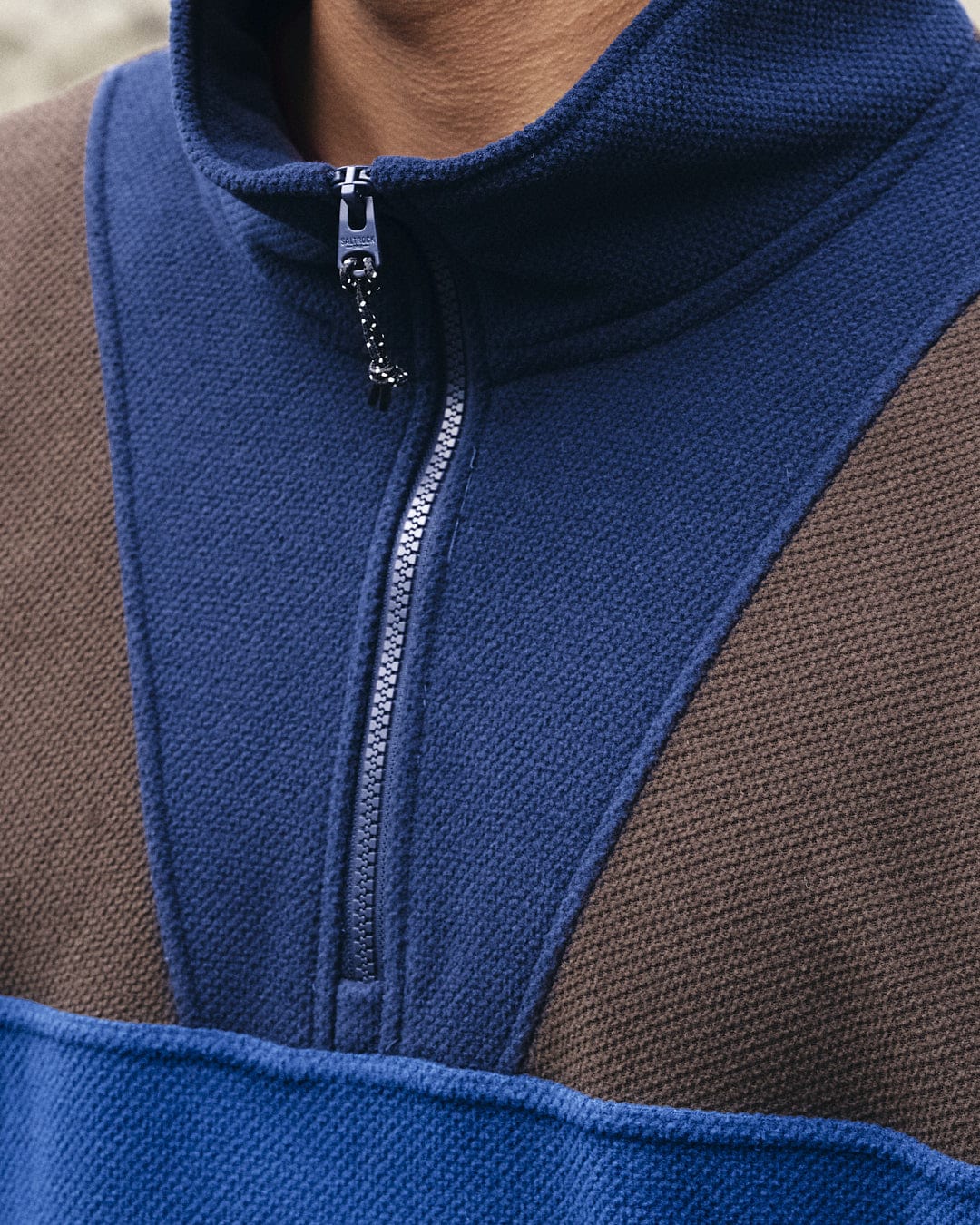 A man showcasing his activewear style in a Saltrock Peninsula Mens 1/4 Zip Pullover Fleece - Blue sweatshirt with blue and brown coloration.