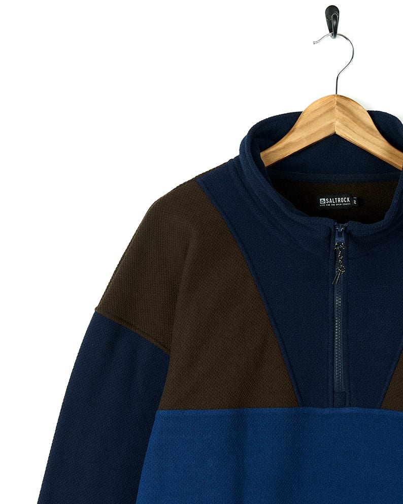 A Saltrock Peninsula - Mens 1/4 Zip Pullover Fleece - Blue sweatshirt, in a stylish combination of blue and brown, hanging on a hanger.