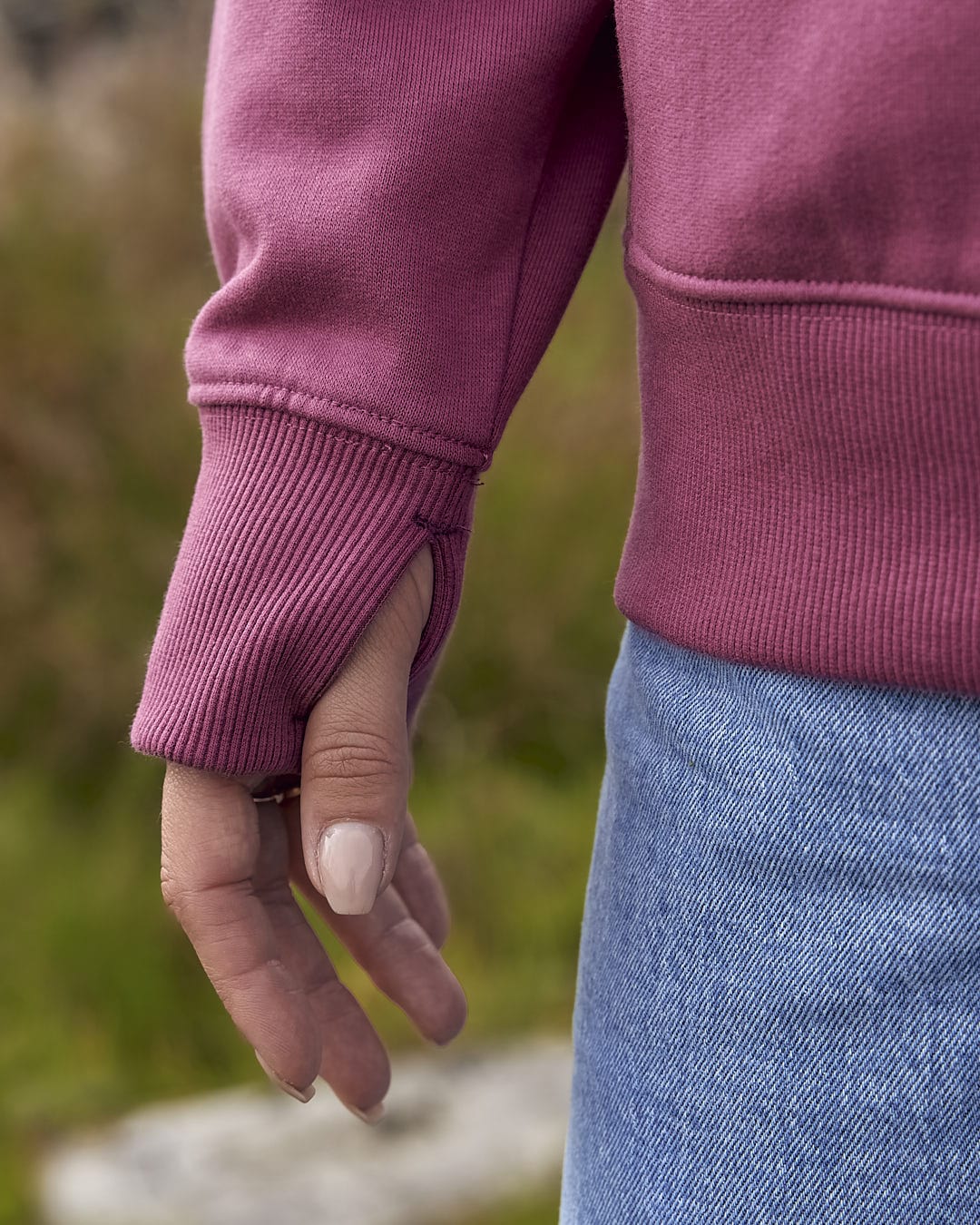 A woman wearing a Saltrock Pennie - Ladies Pop Hoodie - Dark Pink sweatshirt and jeans.