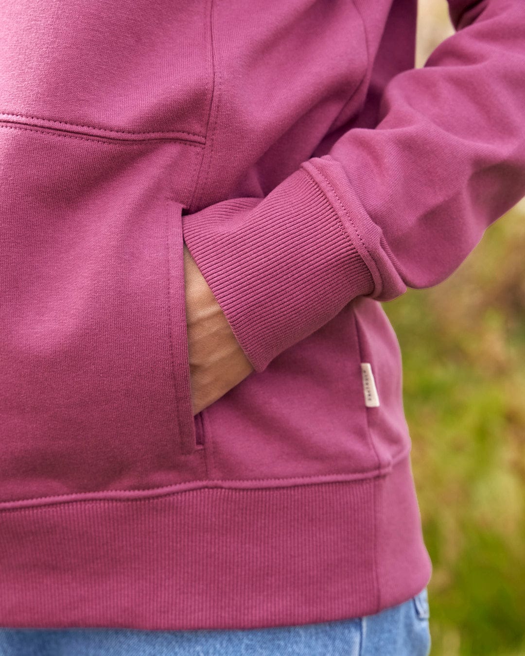 A woman wearing a Saltrock Pennie - Ladies Pop Hoodie - Dark Pink with a pocket.