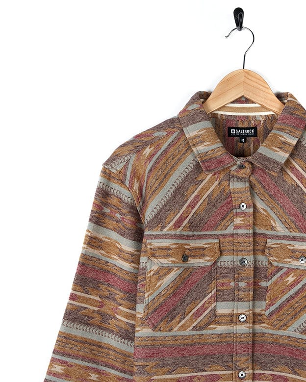 A Saltrock Quinn - Womens Heavy Overshirt - Brown with buttoned cuffs hanging on a hanger.