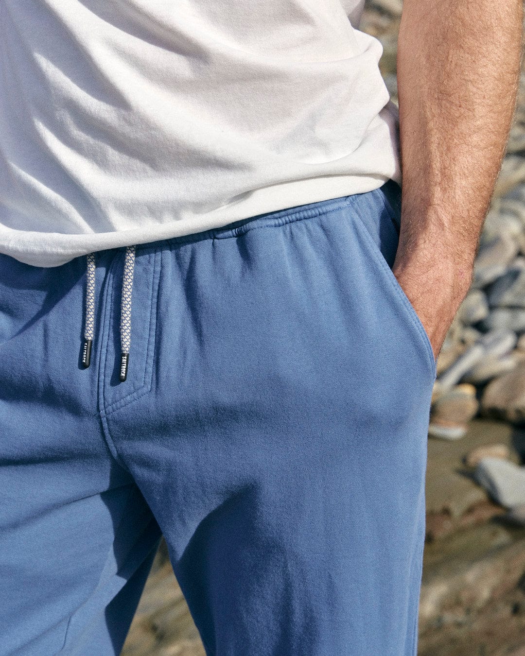 A man wearing stylish blue Ralfen sweatpants by Saltrock and a slim fit white t-shirt.