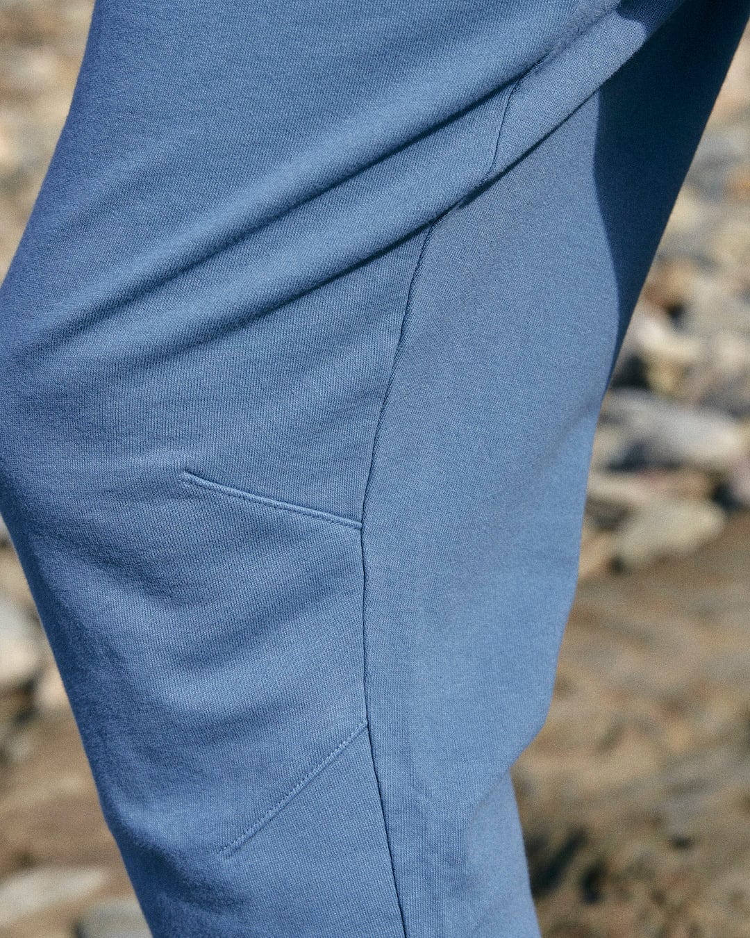 A person is standing on a beach wearing Saltrock Ralfen - Mens Slimfit Sweatpants - Blue.