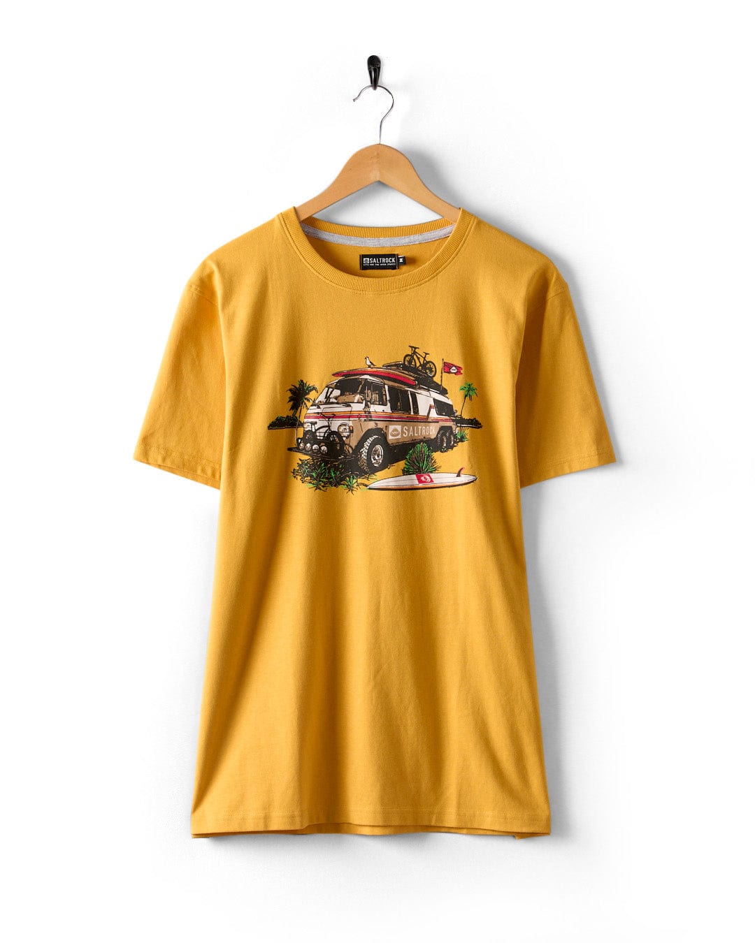 A Saltrock Retro Camper yellow t-shirt hangs on a hanger, showcasing a surf bus, palm trees, and flag in an adventurous design.