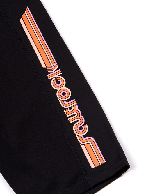 A pair of Retro Ribbon - Womens Cycling Short - Black with a retro print stripe in orange and black. Made from super soft fabric. Brand: Saltrock.
