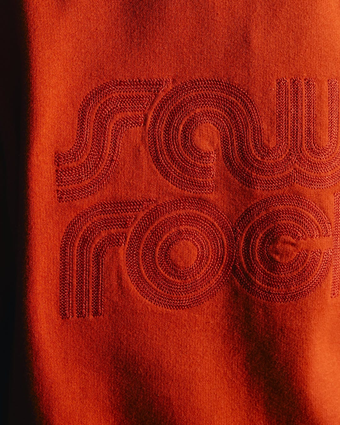 A close up of a Retro Wave Embroidered - Womens Zip Hoodie - Red with the word saw rock on it, featuring contrast blue hood lining and subtle Saltrock branding.