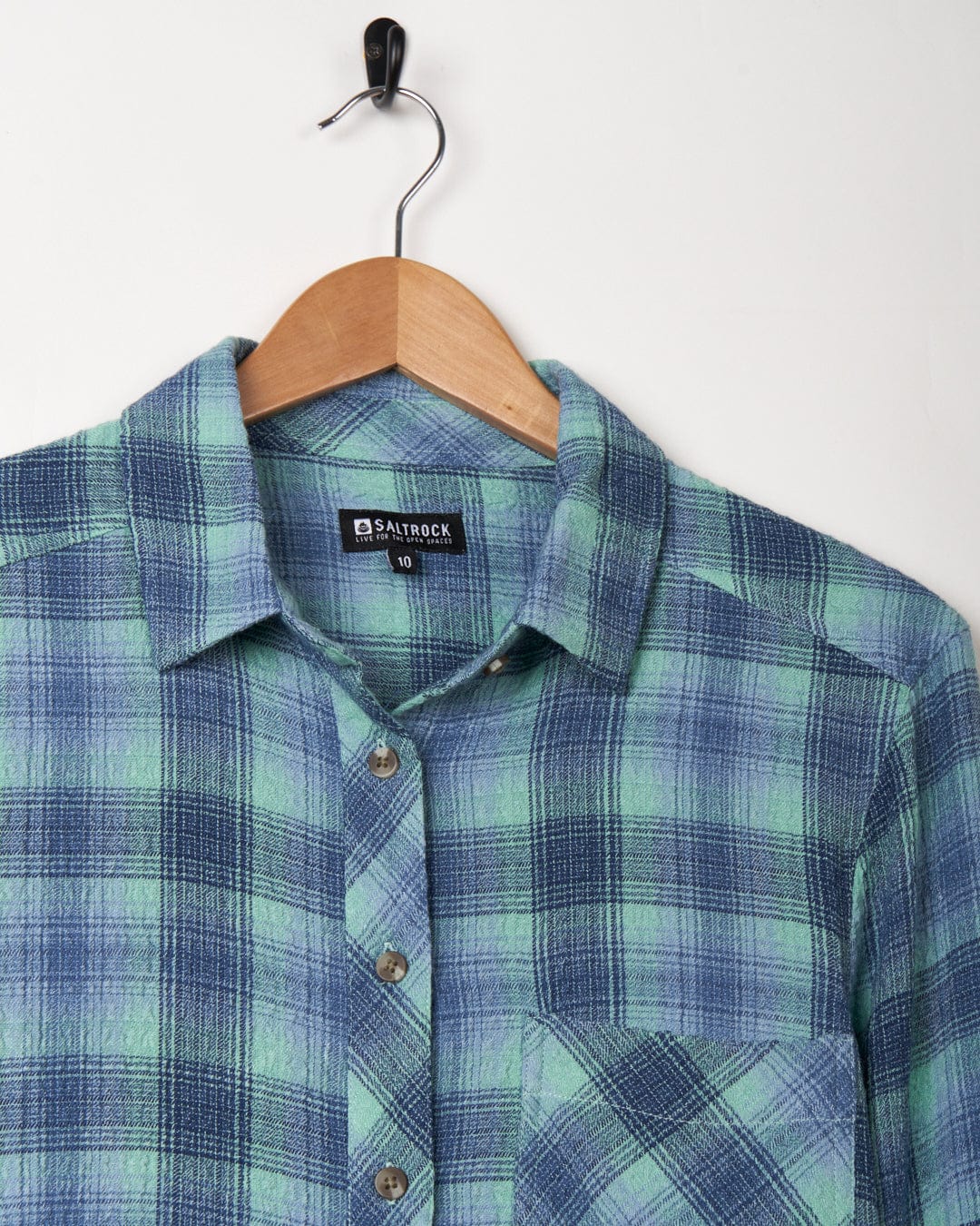 A Rosalin - Womens Longline Shirt - Blue on a wooden hanger against a white background.