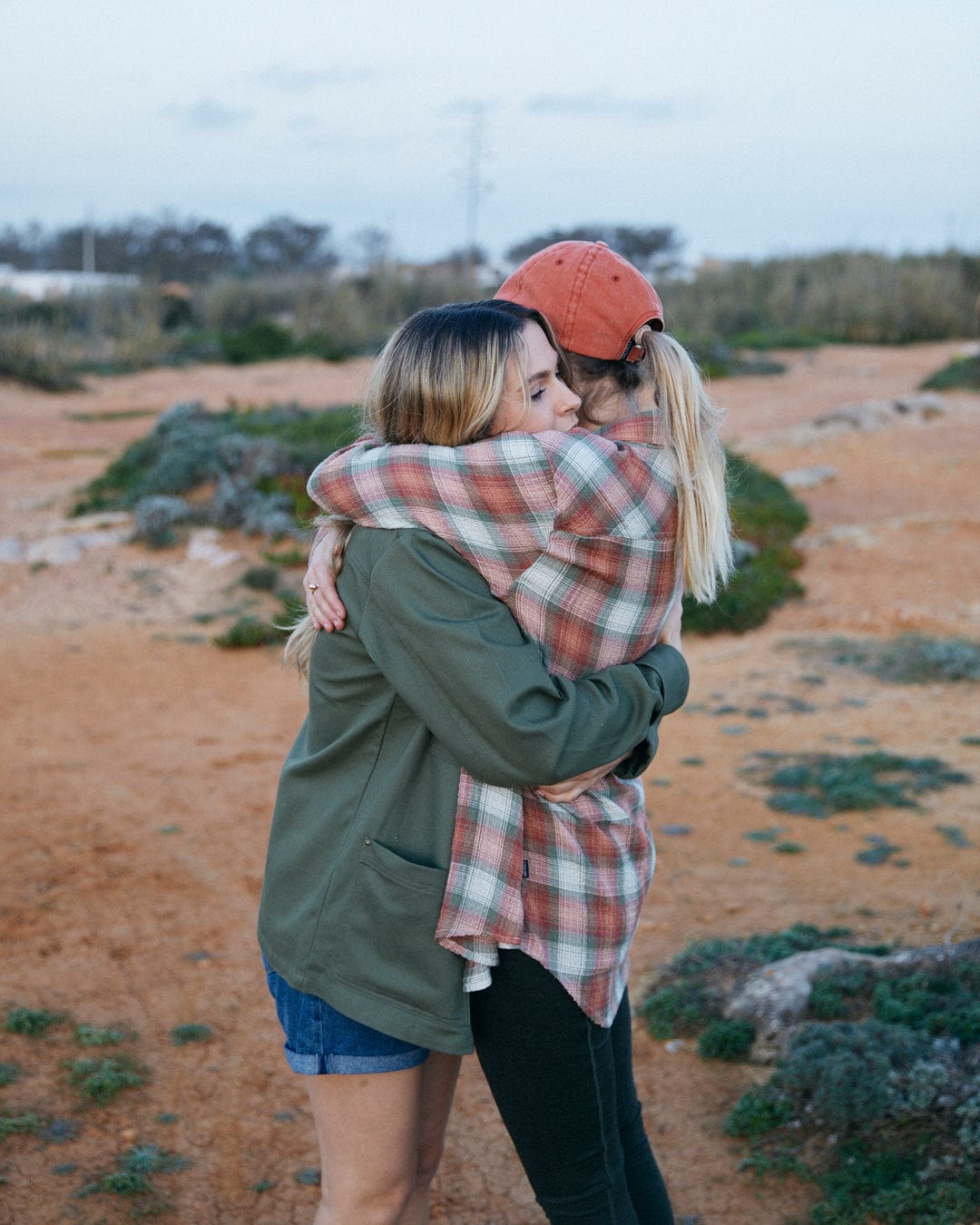 Two people embracing outdoors, one wearing a Saltrock Rosalin - Womens Long Sleeve Shirt in Orange/green with contrasting buttons.