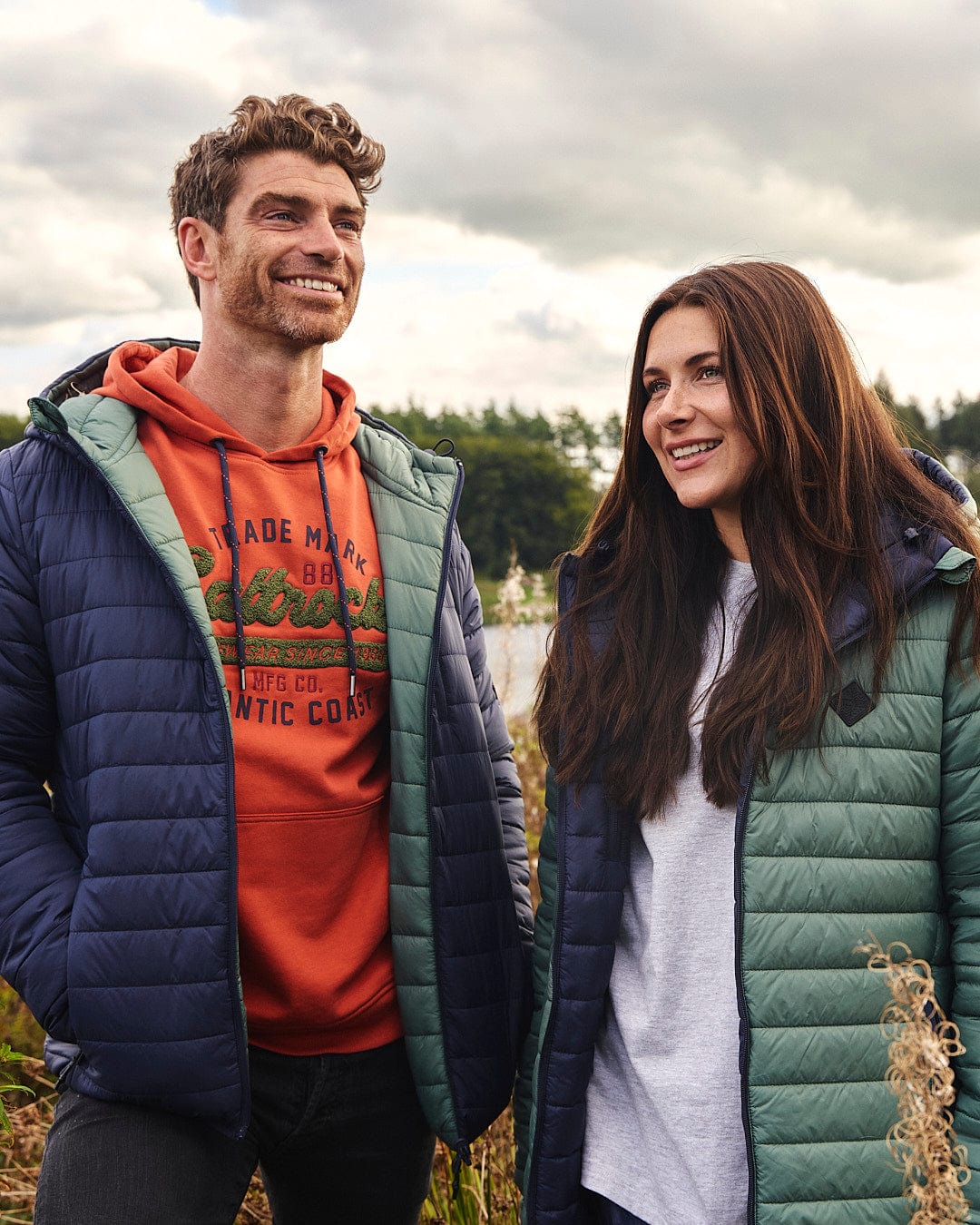 A man and woman standing in a field wearing Saltrock Rusik 2 - Reversible Padded Jackets with zip pockets.