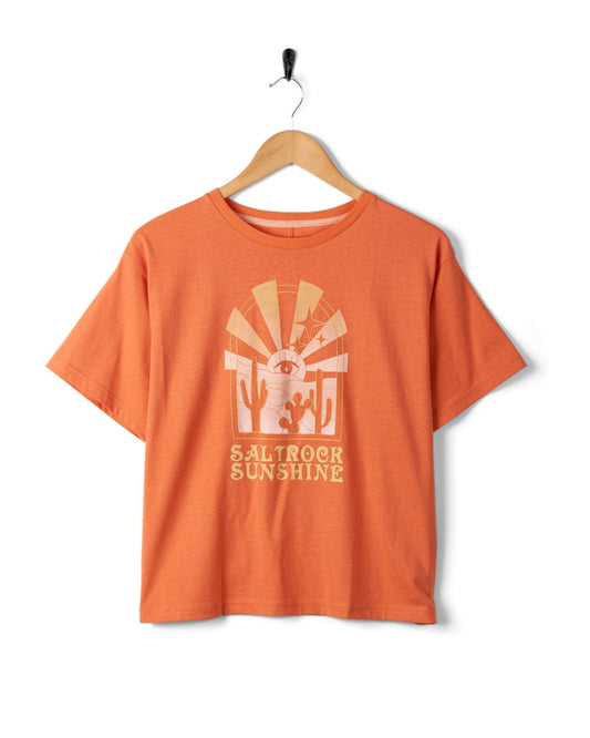 Saltrock Sunshine - Recycled Womens Cropped T-Shirt - Orange with a boxy relaxed fit, featuring mystic desert sunset graphics of cacti and the words "Saltrock Sunshine," hanging on a wooden hanger against a white background.