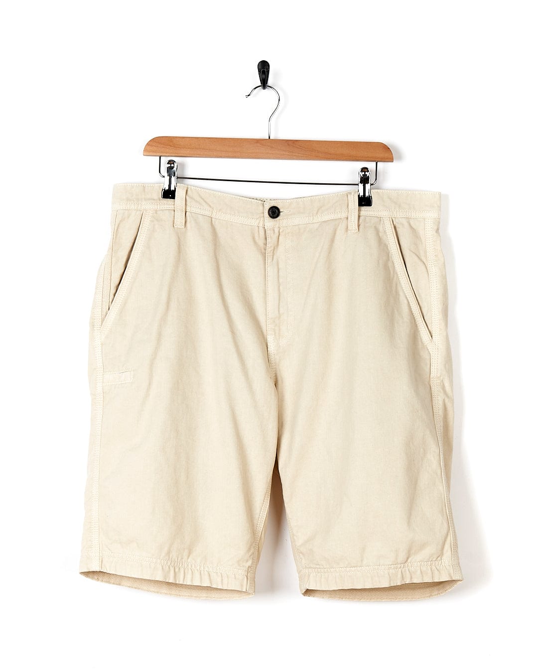 A pair of Sennen - Mens Chino Shorts - Natural by Saltrock hanging on a hanger.