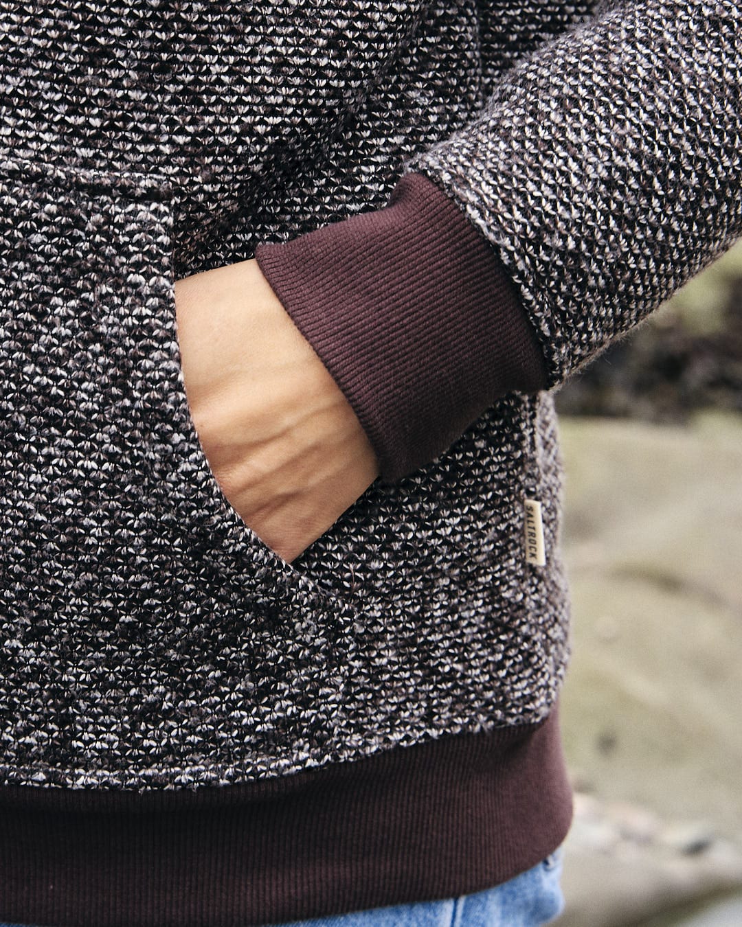 A person wearing a Sofie - Womens Borg Lined Zip Hoodie - Brown, featuring a pocket on the textured knit fabric, with a Saltrock badge.