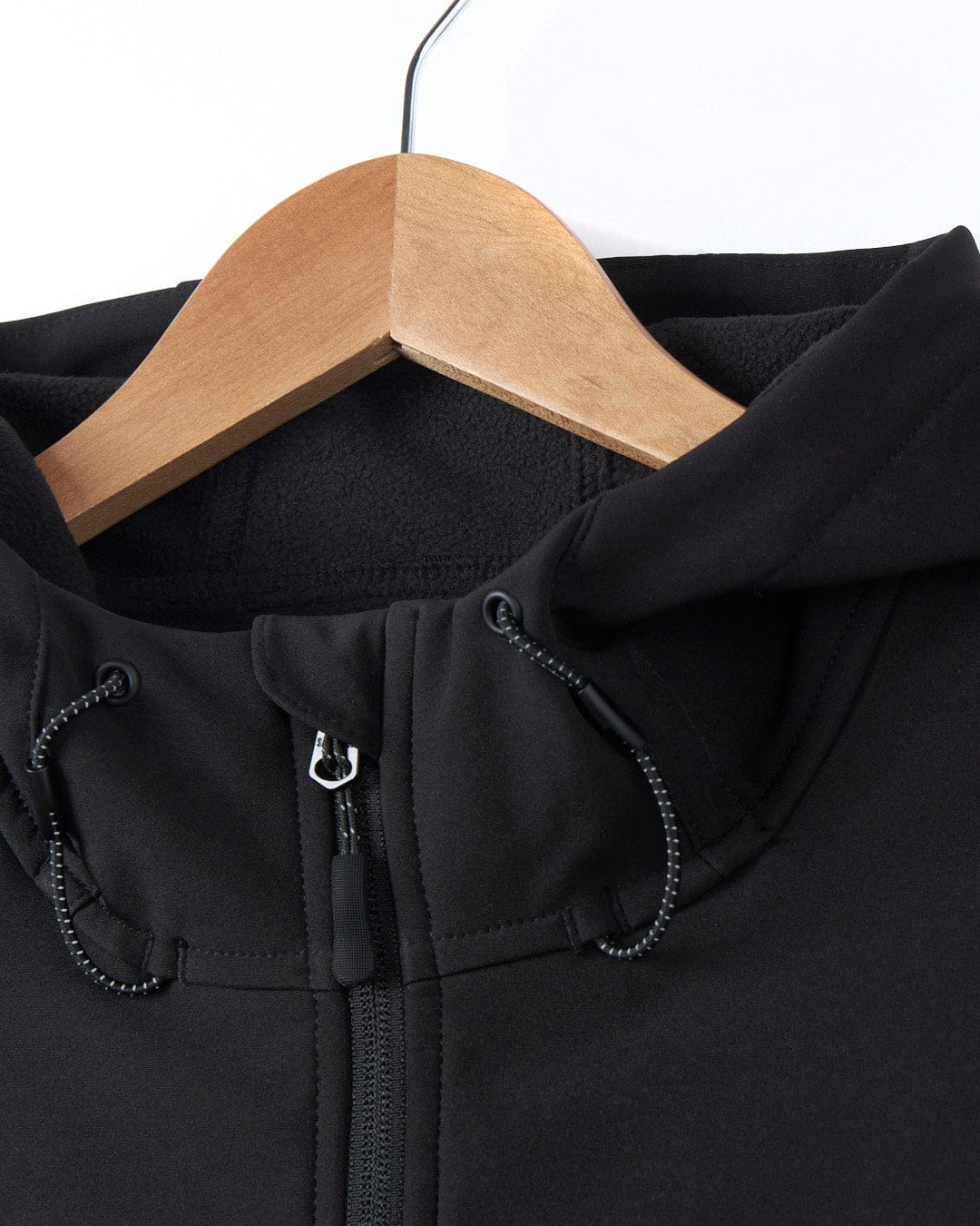 A Saltrock Solar - Womens Softshell Jacket - Black hanging on a wooden hanger.