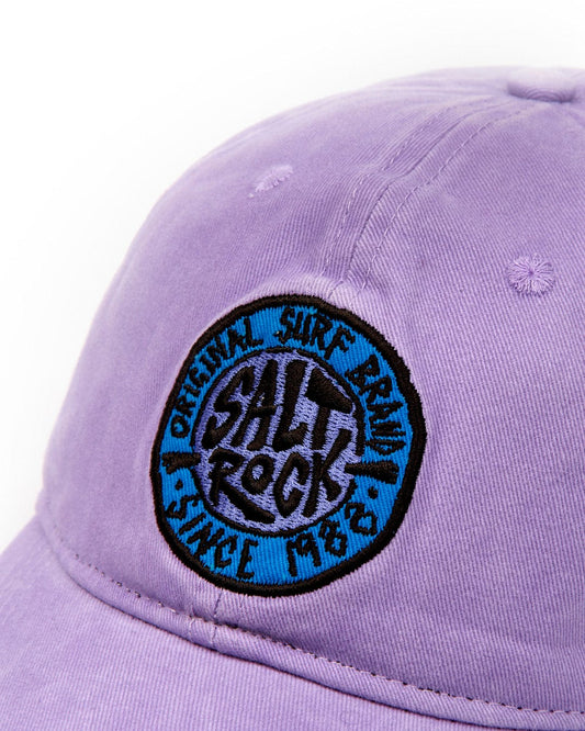 A purple SR Original Cap - Purple baseball cap with a blue and black embroidered logo that reads "Saltrock," featuring an adjustable strap.