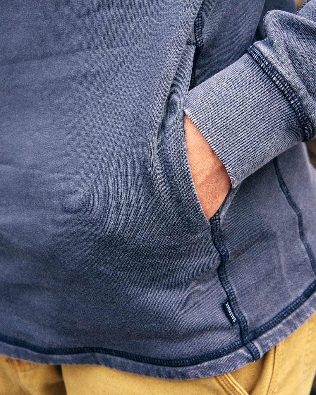 A man wearing a Stellan - Mens 1/4 Neck Sweat - Grey Acid Wash sweatshirt in acid wash blue by Saltrock.