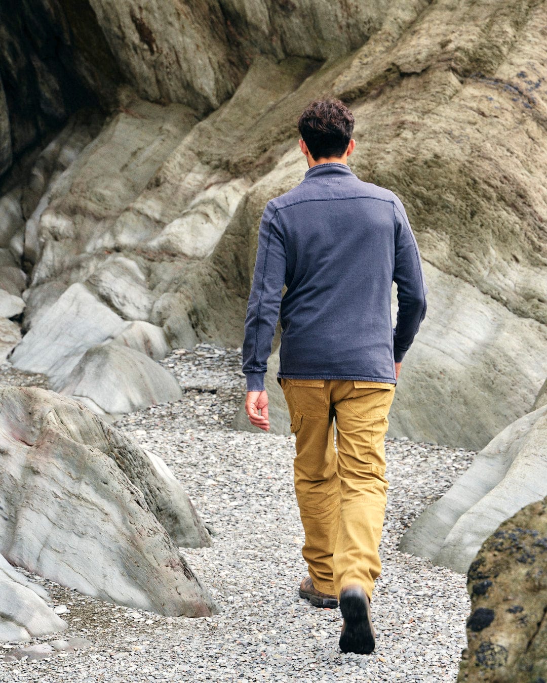 A fashionable man walking down a gravel path wearing the Stellan - Mens 1/4 Neck Sweat - Grey Acid Wash by Saltrock.