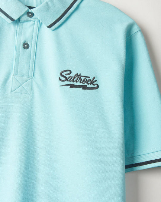 Close-up of a Strike Logo - Mens Short Sleeve Polo Shirt - Light Blue with the Saltrock logo embroidered in black, featuring a collar with navy blue trim.