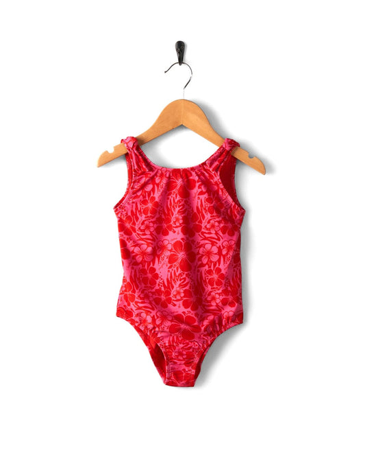 Sunny Hibiscus Saltrock swimsuit for a child hanging on a wooden hanger against a white background.