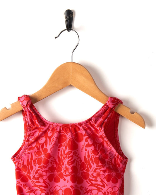 A red Saltrock Sunny Hibiscus-printed children's tank top hanging on a wooden hanger against a white background.