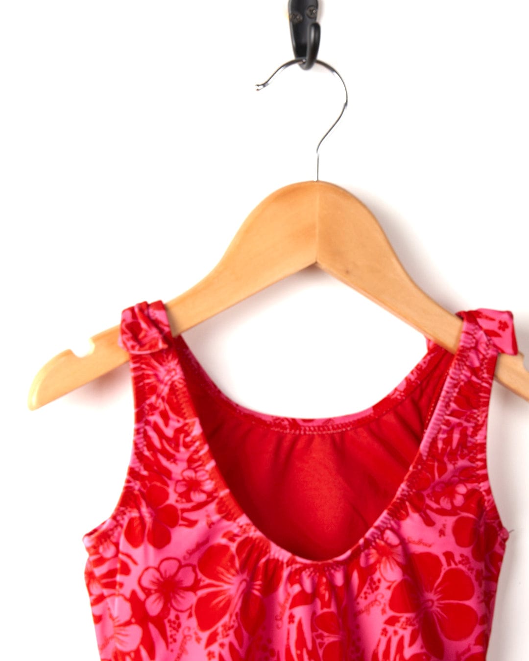 Red floral Saltrock Sunny Hibiscus dress hanging on a wooden hanger against a white background.