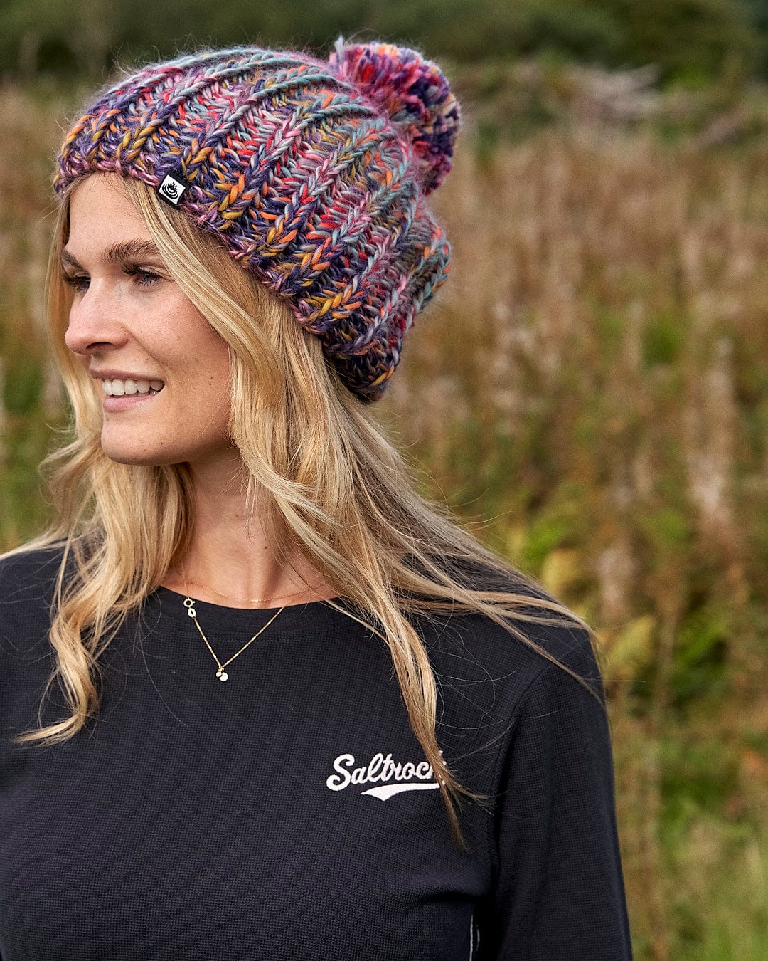 A woman wearing a Saltrock Surprise - Beanie - Multi hat in a field.