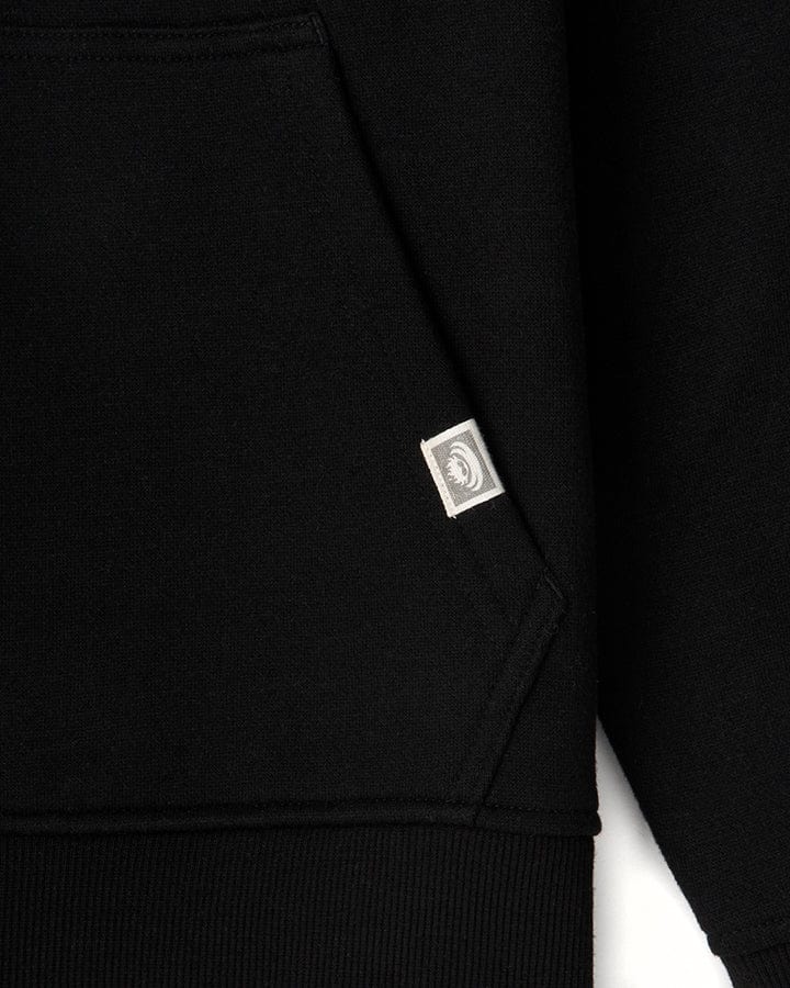 Close-up view of a Saltrock Original - Mens Pop Hoodie in black jersey material with a small, square white label on the edge, featuring a circular Saltrock branding logo or emblem.