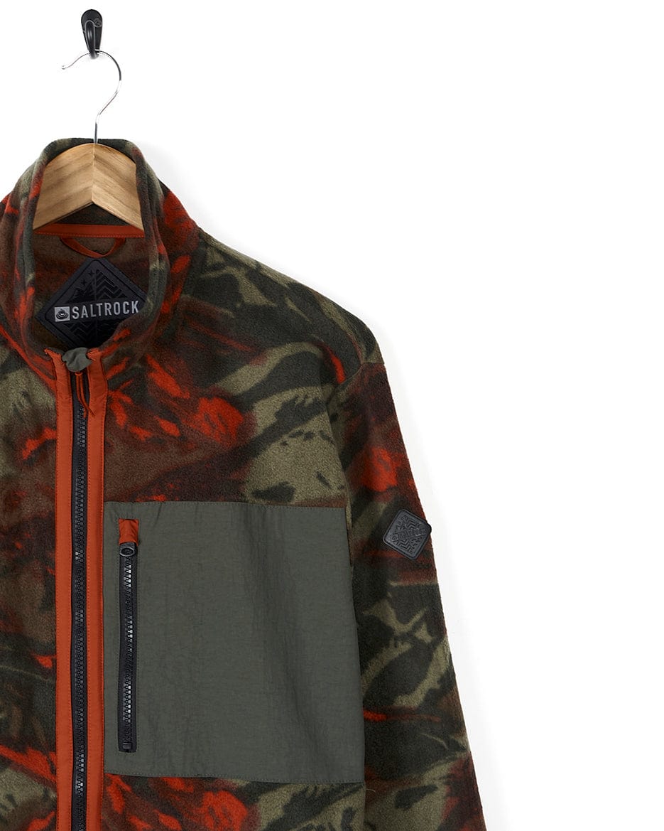 The Saltrock Terran - Mens Zip Thru Fleece - Green/Red jacket with red trims is hanging on a hanger.