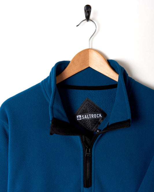 A Theo - Mens 1/4 Neck Fleece - Blue Saltrock jacket hanging on a hanger.