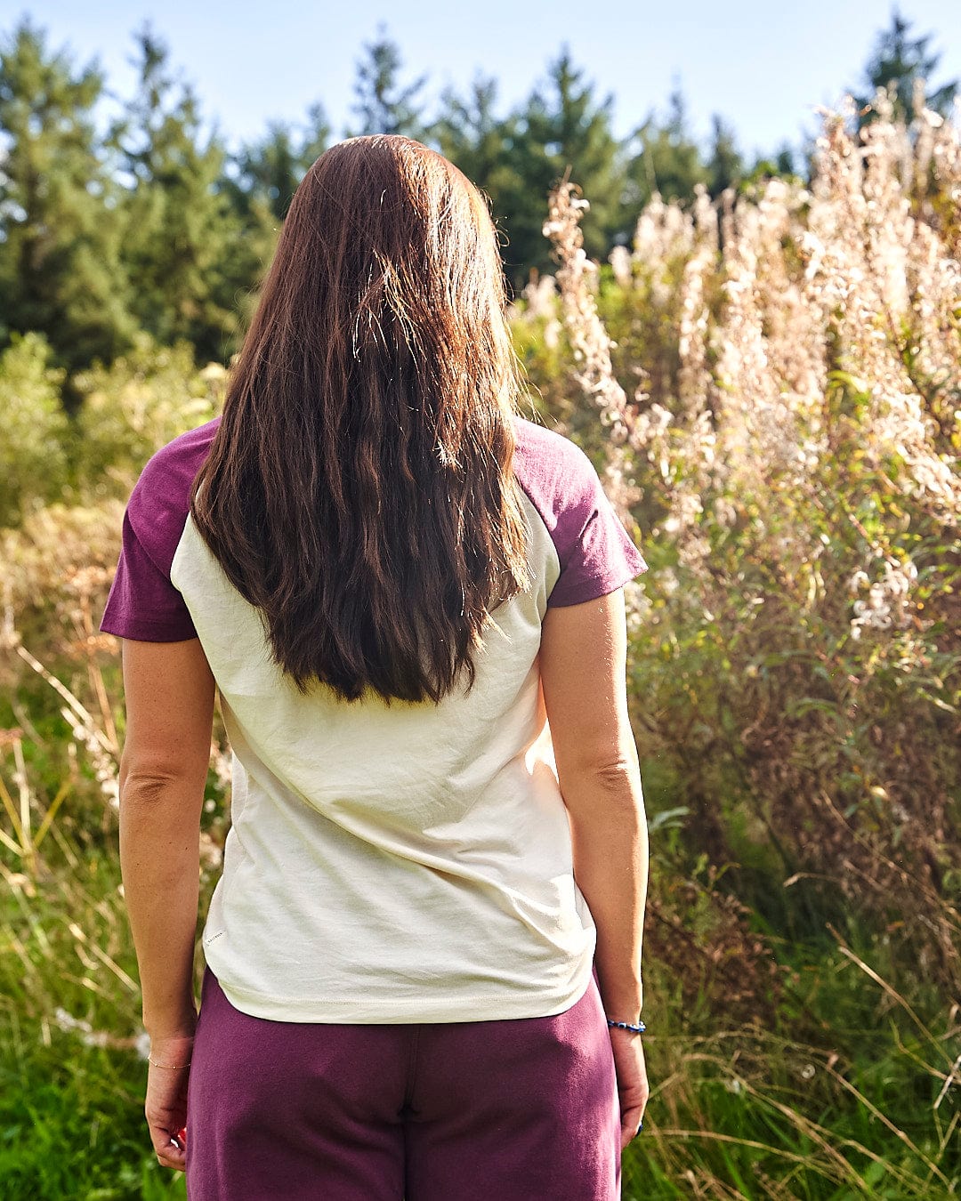 A woman wearing a Saltrock Trademark Floral - Womens Short Sleeve T-Shirt - Cream stands in a field.