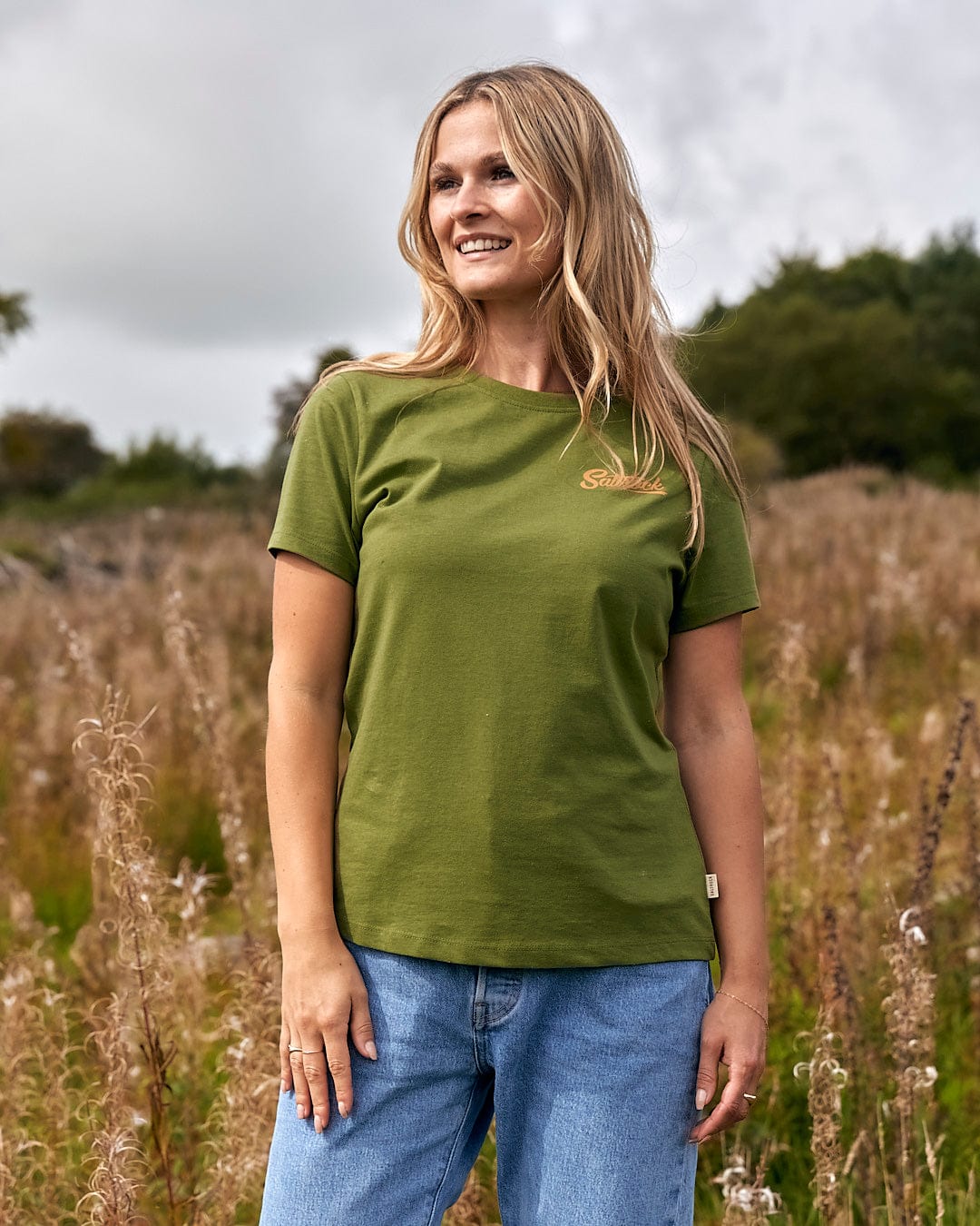 A woman in a Saltrock Trademark - Womens Short Sleeve T-Shirt - Green standing in a field.