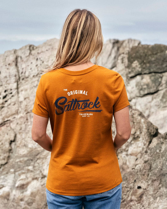 The back of a woman wearing an orange Saltrock crew neck tee.