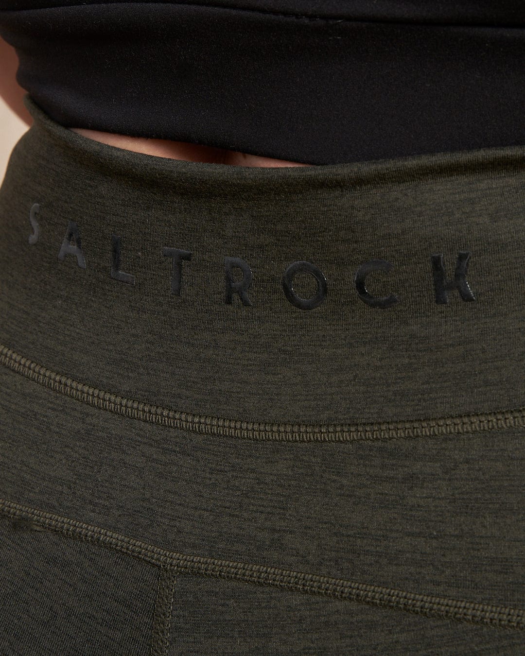 Close-up of the waistband on Saltrock's Trek Women's 4 Way Stretch Outdoor Leggings in dark green, featuring "Saltrock" in black and squat-proof fabric for confident movement.