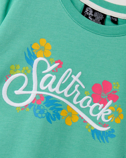 Close-up of a green Tropic - Recycled Kids Short Sleeve T-Shirt with the word "Saltrock print" embroidered in white, surrounded by yellow and pink floral designs.