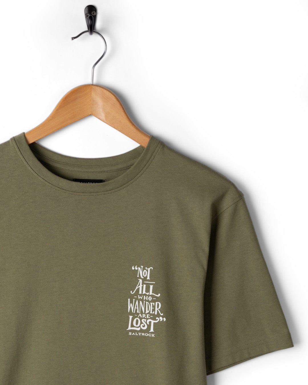 The Saltrock Lost Ships Men's Green Short Sleeve T-Shirt, made from recycled polyester, features "Not all who wander are lost" printed on the front and is displayed on a wooden hanger.