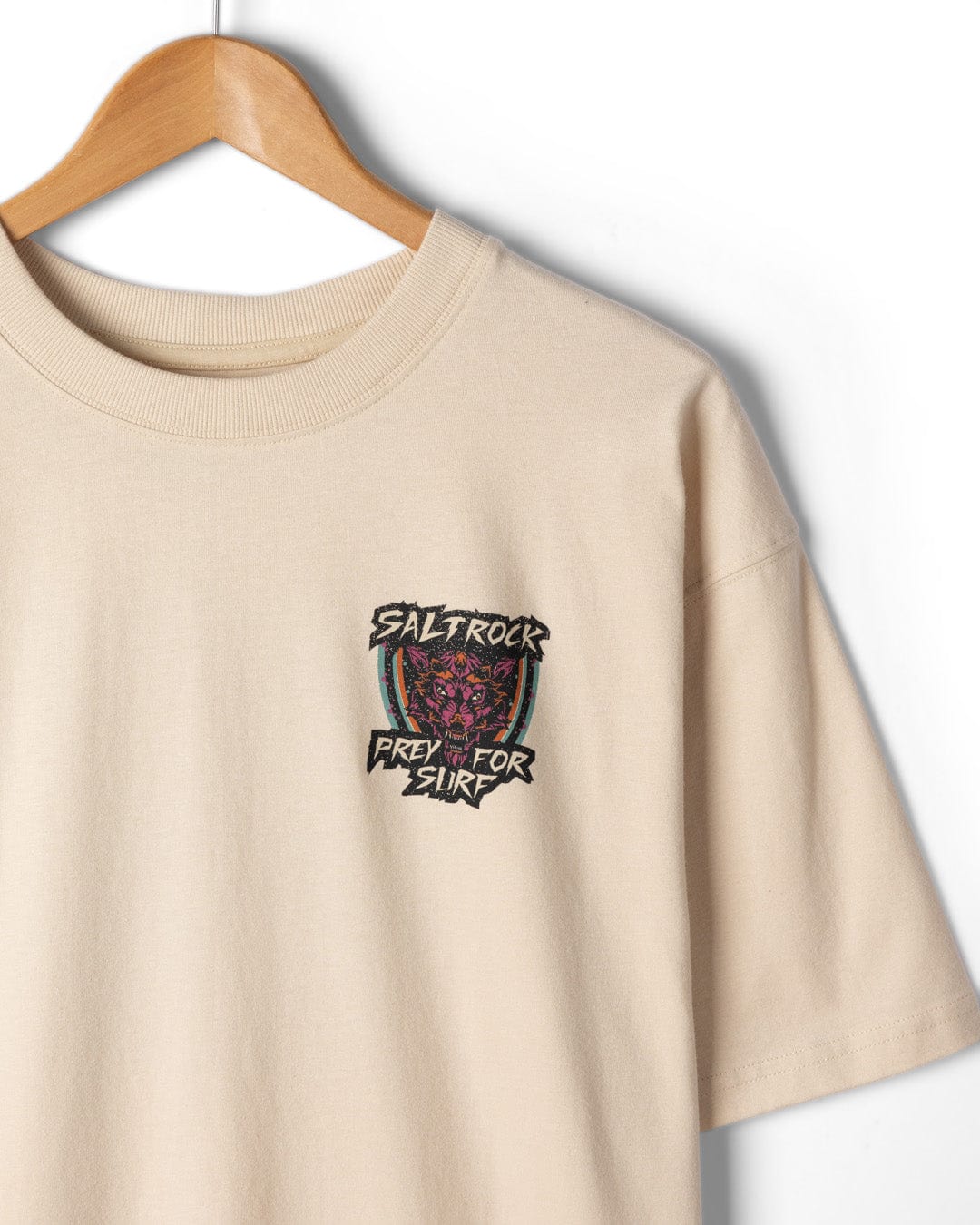 A cream Saltrock Wolfscale II men's oversized short sleeve t-shirt, made from 100% cotton, hangs on a wooden hanger and features a small chest graphic.
