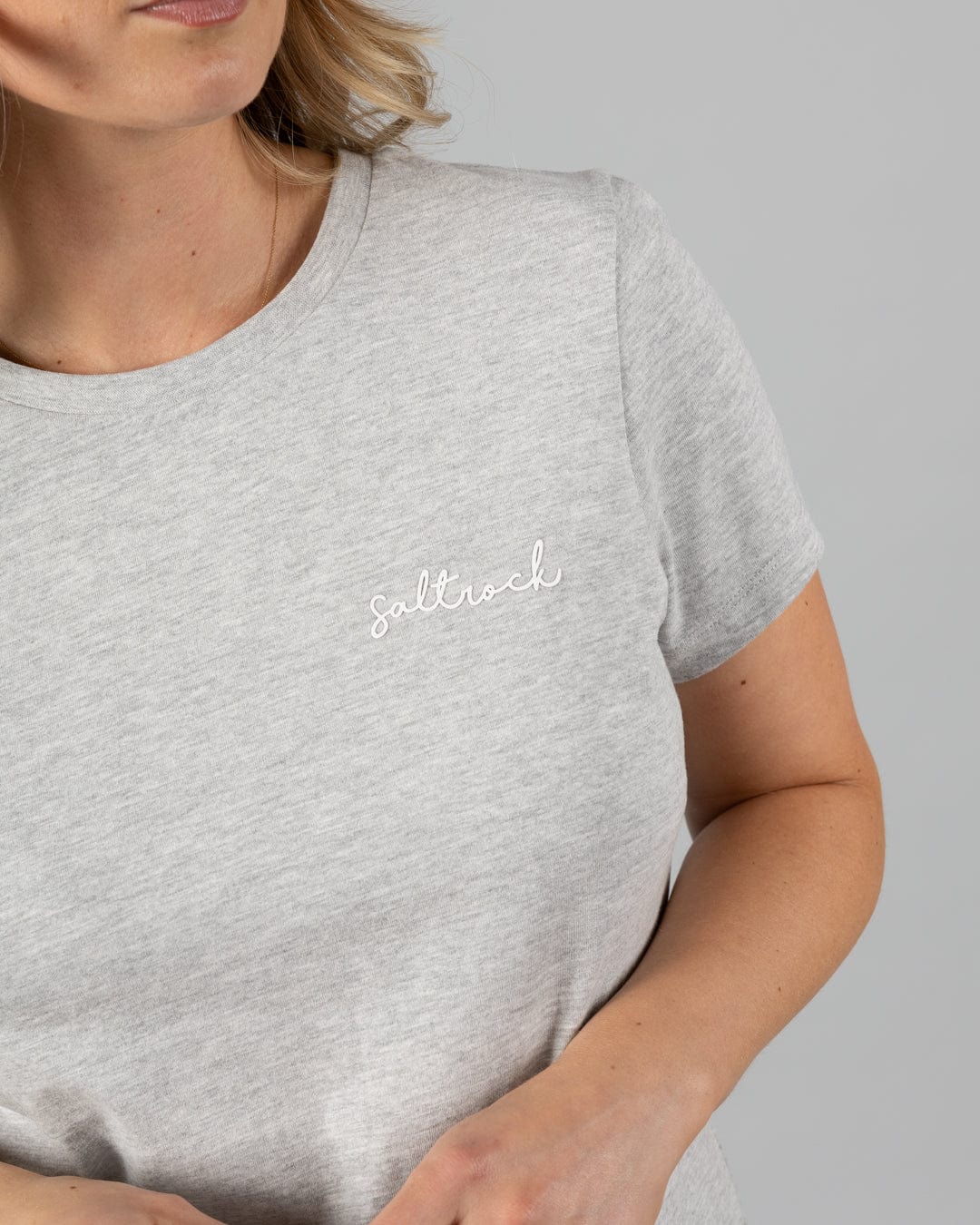 A woman wears the Saltrock Velator Women's Short Sleeve T-Shirt in Grey Marl, featuring a classic crew neck and "Saltrock" embroidered in white on the chest.