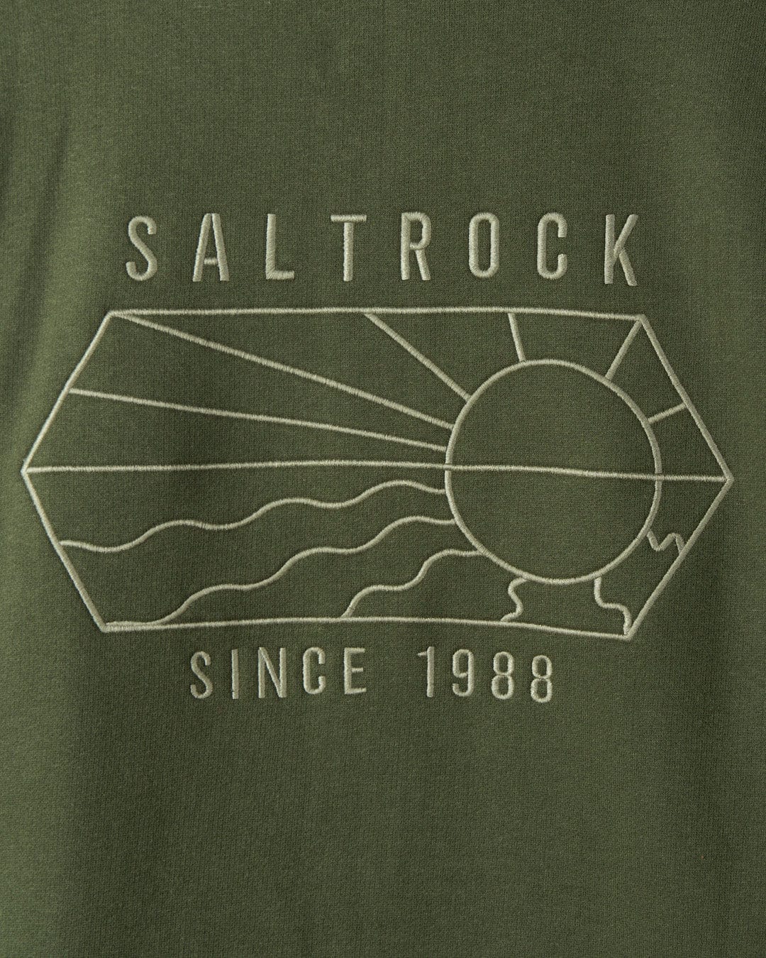 Close-up of a green Saltrock Vantage Outline - Recycled Mens Zip Hoodie - Dark Green with the embroidered logo "Saltrock since 1988", featuring a stylized sun and waves inside a geometric shape.