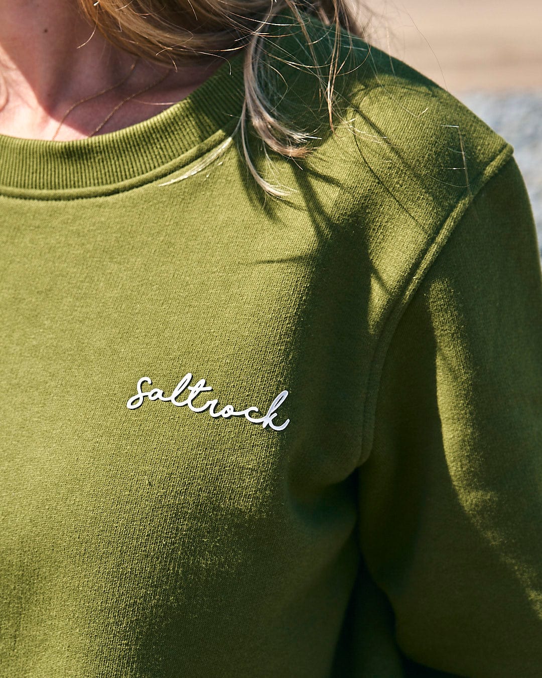 A woman wearing a Velator - Womens Long Sleeve Sweat - Dark Green with the brand name Saltrock on it.