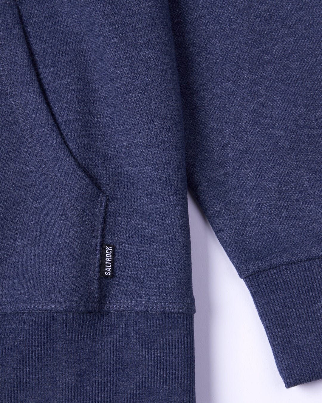 Close-up view of a navy blue Velator - Womens Pop Hoodie by Saltrock showing the soft material and a Saltrock branding label on the side seam.