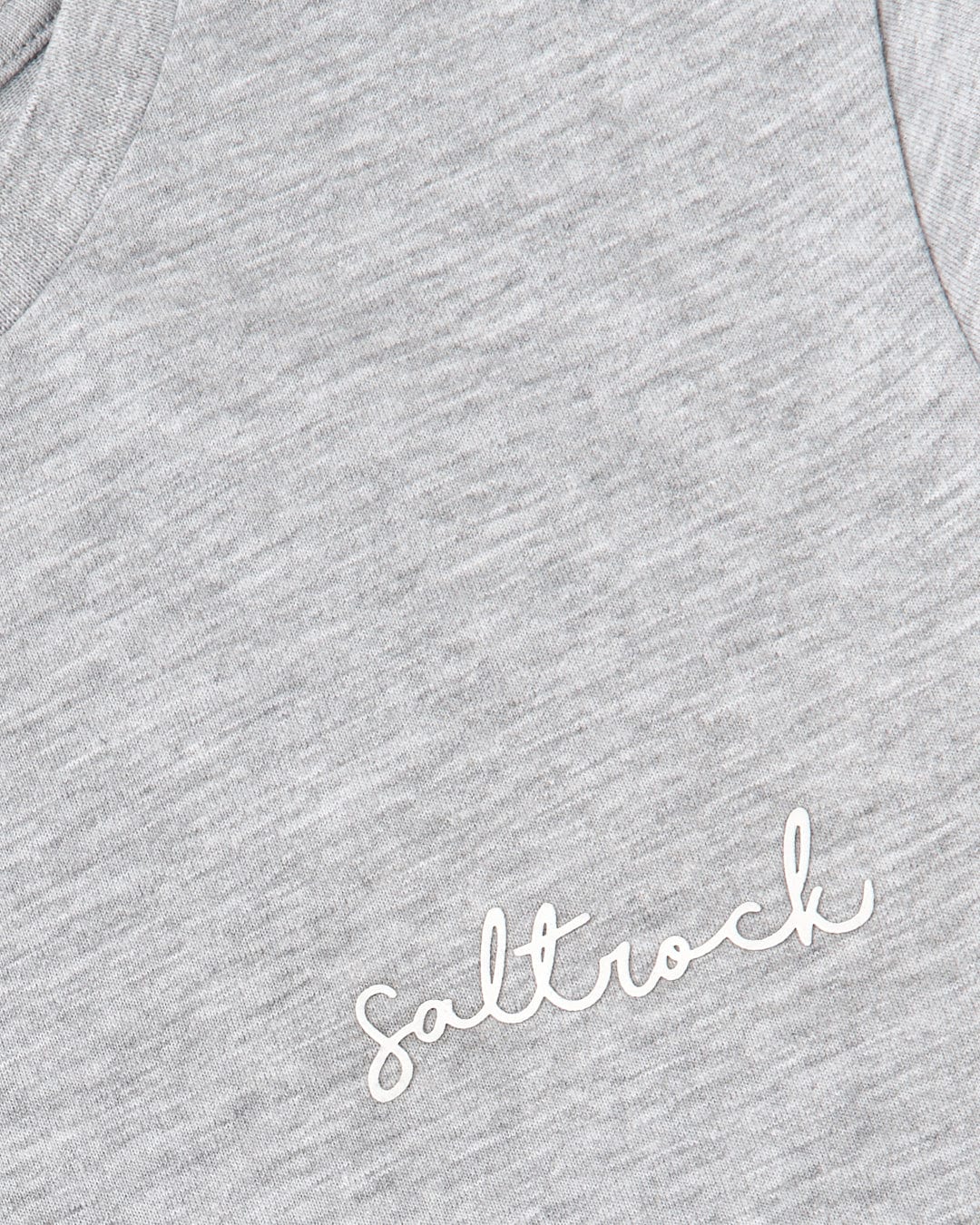 Close-up of a gray fabric texture with the word "Velator" embroidered in white cursive on the chest area by Saltrock.